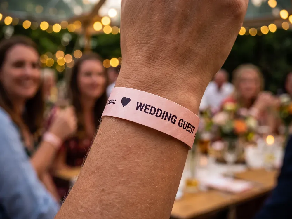 Blush pink wedding guest wristband worn at an evening reception